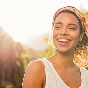 Woman in white tank top outside smiling