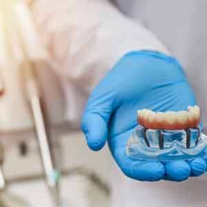 a dentist holding a model of an implant denture